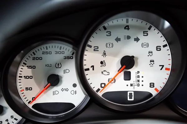 On-board computer and white dashboard of a luxury premium sedan. Tachometer, speedometer. Red arrows on the dashboard.