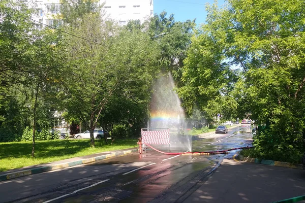 Burst pipe. The incident in the city. The work of public services. From the leaky hose gushing water into the sky. Rainbow in the air.