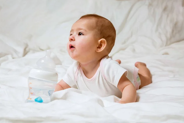Triste Et Pleurant Bebe Fille Couchee Sur Le Lit Blanc Avec Une Bouteille D Eau Speciale Avec Mamelon Il Essaie De La Ronger Dentition Soins De Sante Un Seul Stock Photo