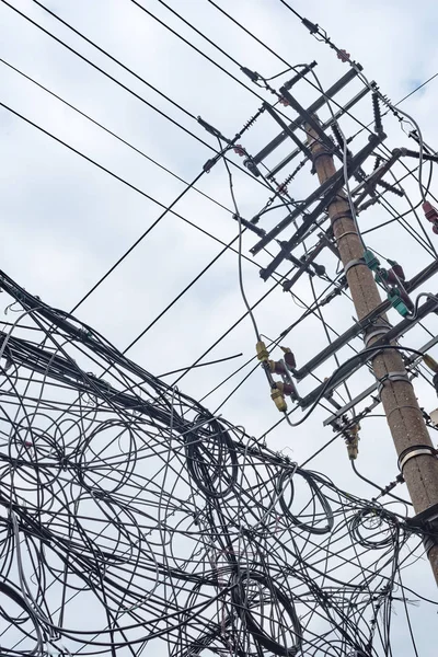 Telefonstolpe och kaotisk röra av kablar mot himlen — Stockfoto