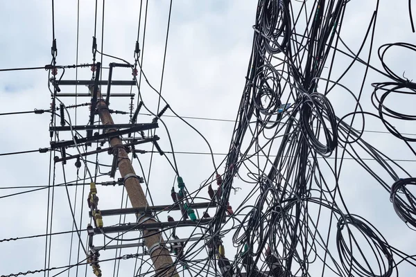 Telefonstolpe och kaotisk röra av kablar mot himlen — Stockfoto