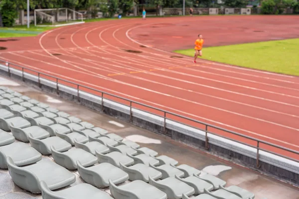 Focus selettivo sui posti in uno stadio con un uomo in corsa — Foto Stock