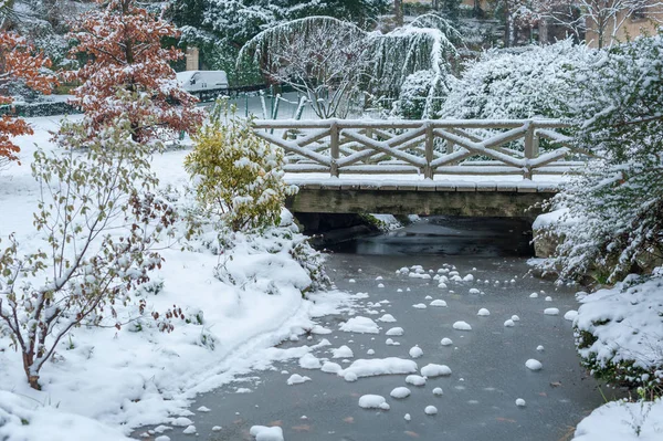 Ruscello ghiacciato e ponticello sotto la neve in inverno — Foto Stock