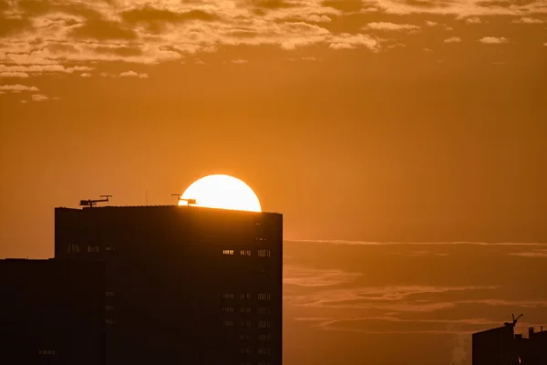 Sun rising behind a building