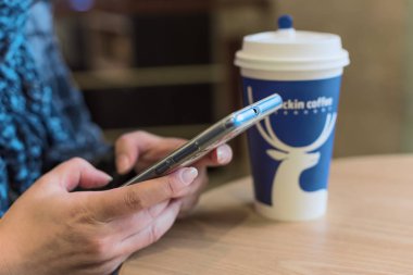 Kadın bir smartphone ve Luckin kahve Kupası bir tablo ile