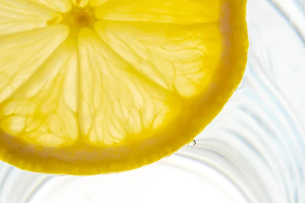 Zitronenscheibe in einem Glas Wasser hinterleuchtet — Stockfoto