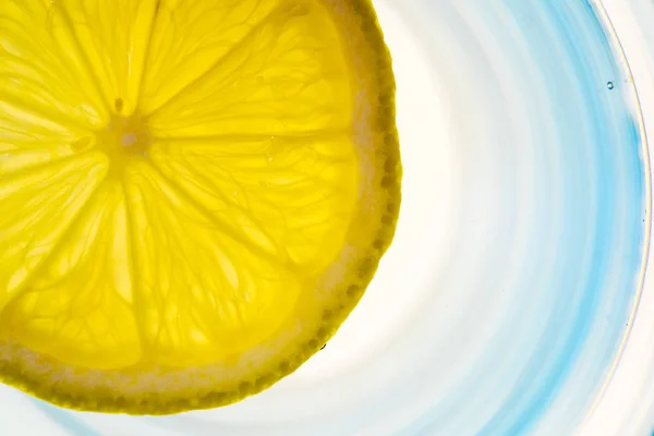 Zitronenscheibe in einem Glas Wasser hinterleuchtet — Stockfoto
