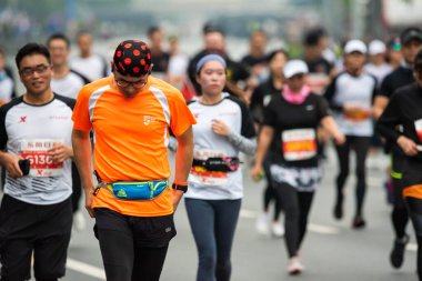 Chengdu maratonunda turuncu tişörtlü bir sporcu yürüyor.