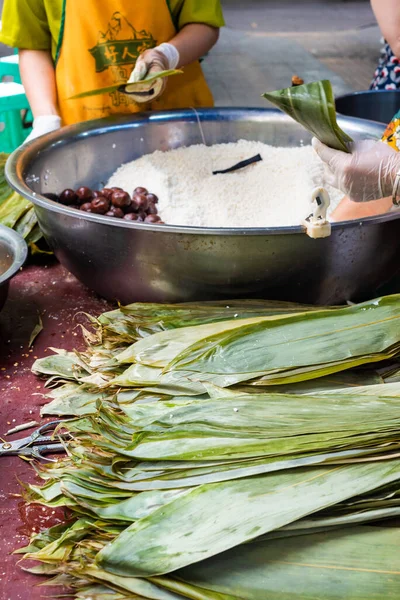 Pessoas que preparam ZhongZi - prato de arroz chinês tradicional em folhas de bambu — Fotografia de Stock