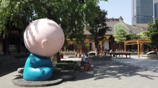 Tempio buddista di Daci con una scultura di manga a forma di monaco sotto un albero in una giornata di sole a Chengdu — Video Stock