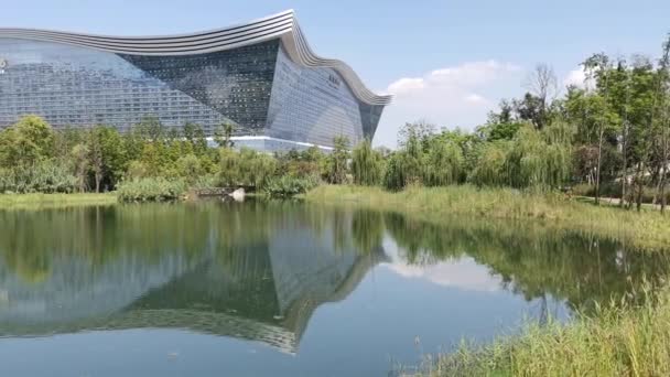 Edificio del Centro Global del Nuevo Siglo reflejándose en un lago en un día soleado con cielo azul claro — Vídeos de Stock