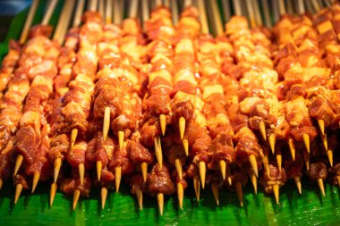 Chengdu, Sichuan 'da, canlı salamura edilmiş et şişleri hareketli bir sokak pazarında ustalıkla düzenlenir. Her şiş, baharatlı salamurayla parıldıyor, vitrinlerde taze et parçaları hazır.