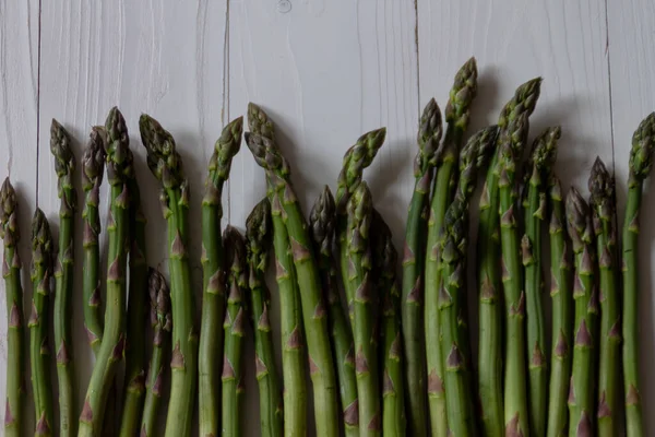 Groene asperges op een witte houten ondergrond. Gezond eten concept. Vlakke plaat — Stockfoto