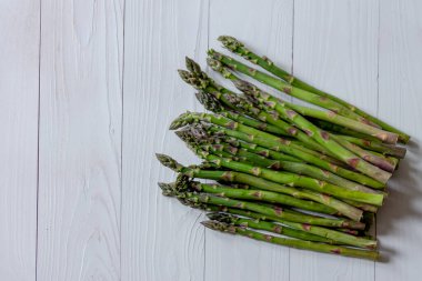 Beyaz ahşap arka planda yeşil kuşkonmaz. Sağlıklı beslenme konsepti. Düz yatıyordu