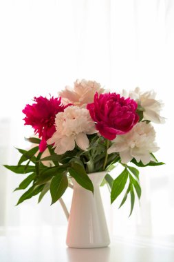 Beyaz ve pembe peonies vazoda beyaz masada