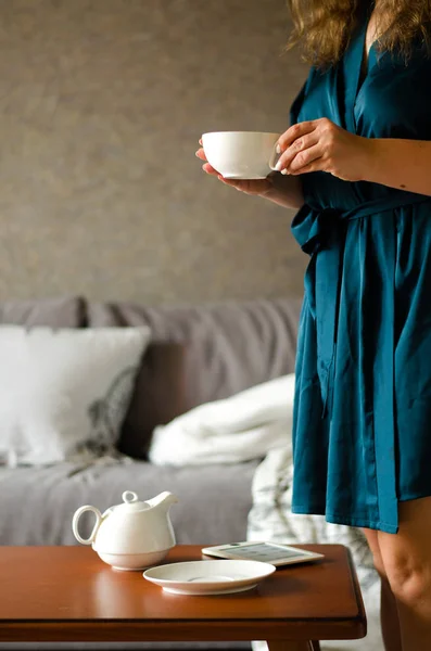 Accogliente interno casa con teiera e donna in possesso di una tazza di tè . — Foto Stock