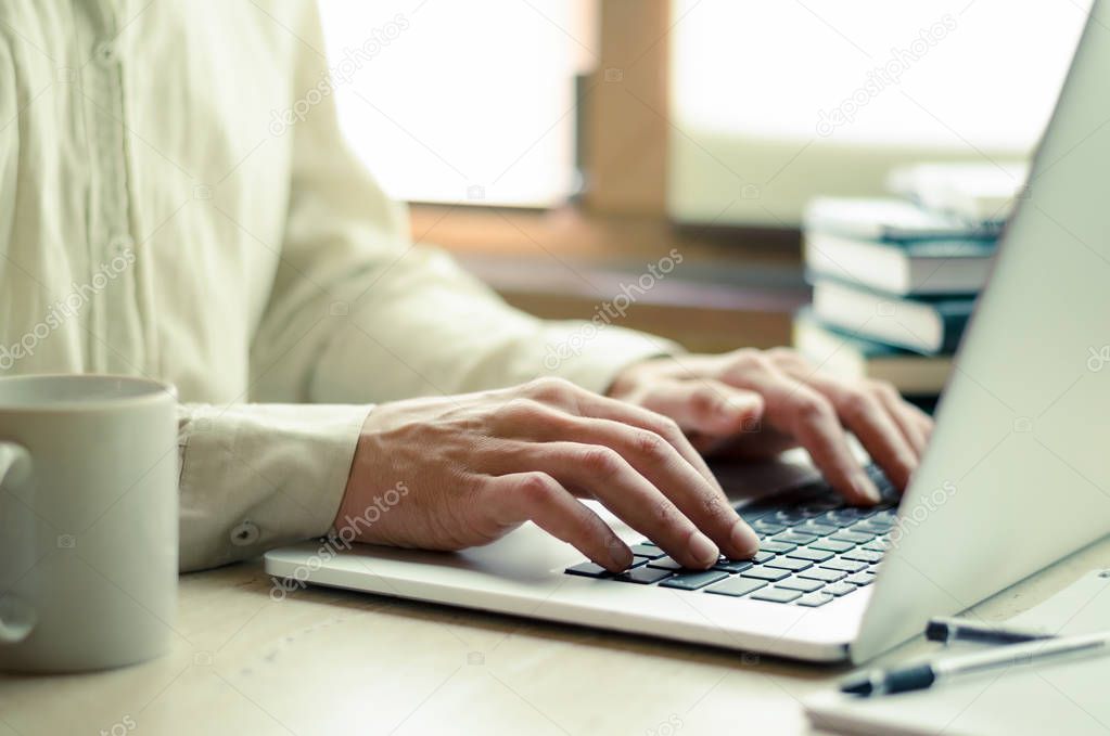 Man working on laptop, with cup of coffee