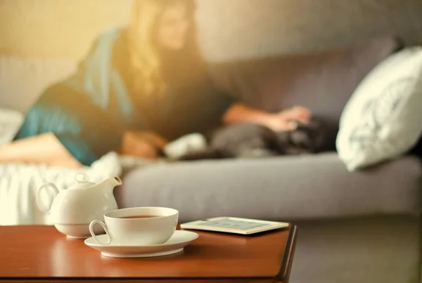 Interior acolhedor casa com bule, xícara de chá e eBook — Fotografia de Stock