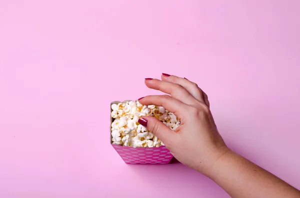 Papierschachtel mit Popcorn auf rosa Hintergrund — Stockfoto