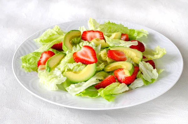 Ensalada con aguacate, fresas y lechuga sobre fondo blanco Imagen de stock