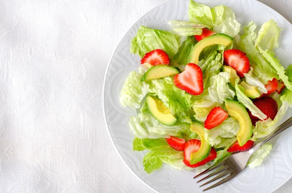 Salat mit Avocado, Erdbeeren und Salat auf weißem Hintergrund Stockfoto