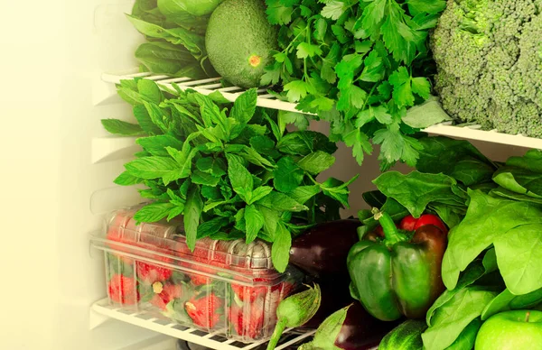 Greens, fruits and vegetables in fridge. Vegan, raw, healthy lifestyle concept