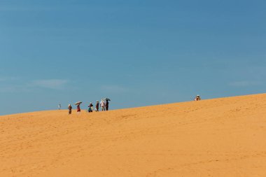Mui Ne, Vietnam - Ocak 2014: Çölde şemsiyeli Asyalı turist grubu / Mui Ne, Vietnam 'da kırmızı kum tepeciği