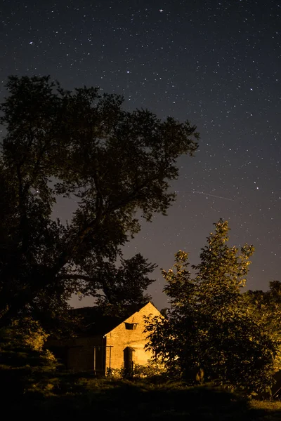 house in rural landscape at night with starlit sky