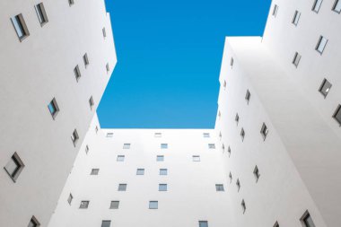 Apartman avlusuna bakıyorum. Bina cephesi, mahkeme ve mavi gökyüzü. 