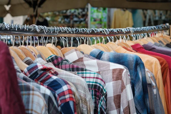 Loja de moda em segunda mão, close-up de camisas penduradas em pendurar — Fotografia de Stock