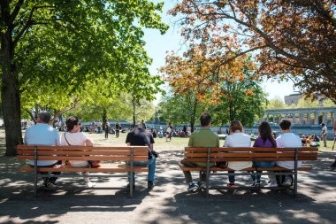 Berlin, Almanya - Nisan 2019: Berlin, Almanya 'da güneşli bir yaz gününde Park' taki bankta oturanlar