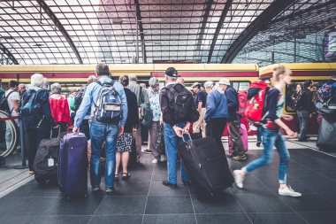 Tren istasyonunda bavulları olan bir grup yaşlı insan.