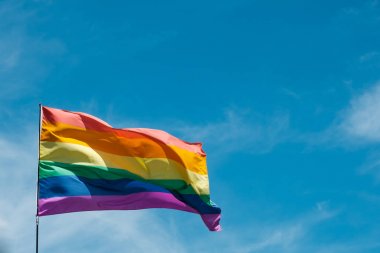 Mavi gökyüzü kopya alanı ile sallayarak gay gökkuşağı bayrağı