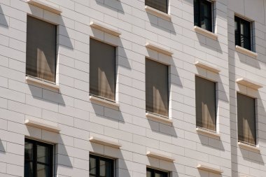 Pencereler kapalı panjurlar ve güneşlikler ile ön cephe oluşturur