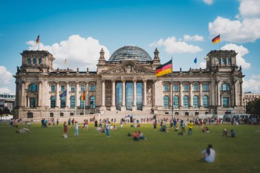 Reichstag binasının önündeki çayırda birçok kişi (Almanca
