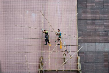 Hong Kong, Kasım 2019: İnşaat alanındaki işçiler Hong Kong 'daki ev cephesinde bambu iskelesi inşa ediyorlar