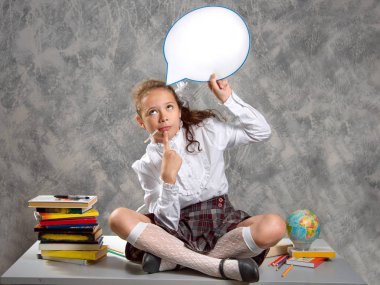 Liseli kızlar okul üniformalı masaya oturur ve komik balon ile düşünüyor. Yeni öğretim yılı. Çocuk eğitim kavramı.