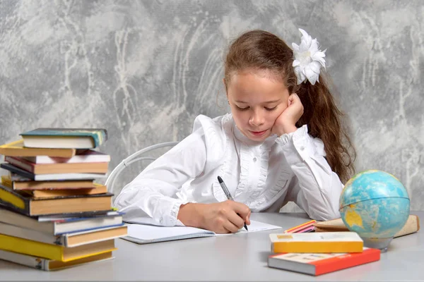 那个穿校服的女学生坐在桌旁 把一些东西写在笔记本上 回学校去新的学年 儿童教育概念 — 图库照片