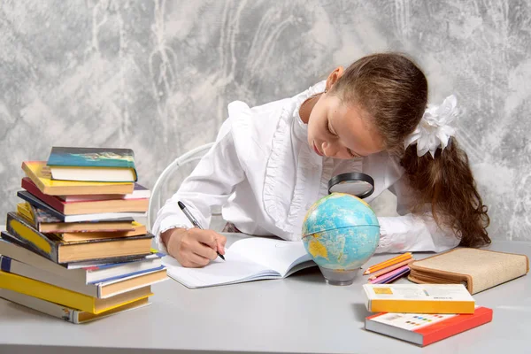 Het Schoolmeisje Schooluniform Een Globe Door Een Vergrootglas Kijken Schrijven — Stockfoto