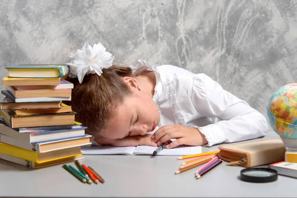 The schoolgirl tired to do homework task and fell asleep at the table. Back to school. The new school year. Child education concept.