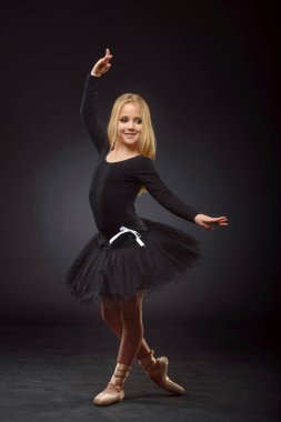 Bir siyah tutu ve siyah bir arka plan üzerinde poz pointe uzun saçlı sevimli küçük balerin