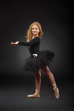 Bir siyah tutu ve siyah bir arka plan üzerinde poz pointe uzun saçlı sevimli küçük balerin