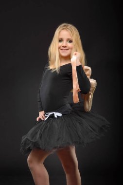 Bir siyah tutu ve siyah bir arka plan üzerinde poz pointe uzun saçlı sevimli küçük balerin