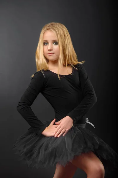 Bailarina bonito pouco com cabelos longos em um tutu preto e ponteiro posando em um fundo preto — Fotografia de Stock