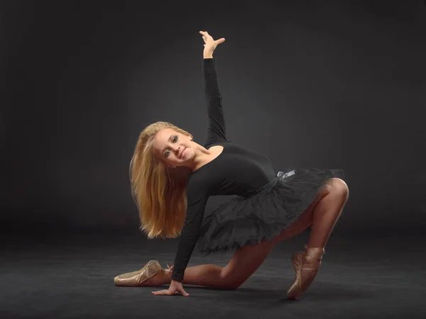 Linda bailarina con el pelo largo en un tutú negro y puntita posando sobre un fondo negro — Foto de Stock