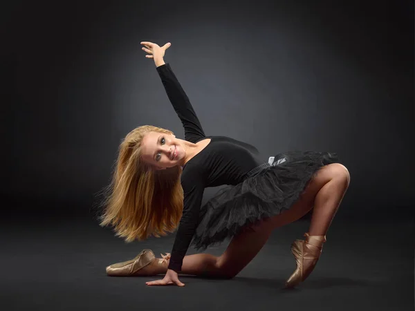 Linda bailarina con el pelo largo en un tutú negro y puntita posando sobre un fondo negro — Foto de Stock