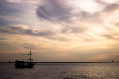 Bir Yelkenli şu zinciri adanın sakin bir desteği hakkında gün batımında silüeti