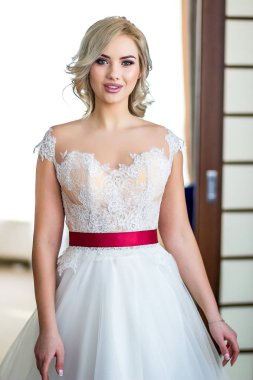 Güzel sarışın zarif gelin düğün makyaj ve vintage koltukta oturan uzun saç modeli