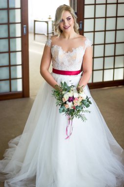 Büyük buket gül ve peonies çekici sarışın gelin kameraya doğru görünüyor