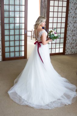 Gelişen peçe içinde güzel bir gelin buketi onun elinde tutar.